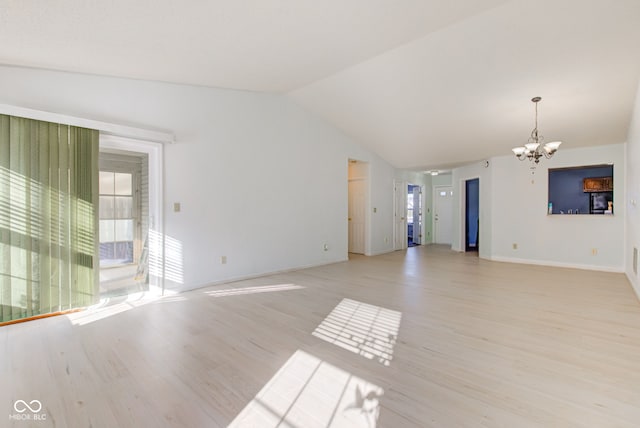 unfurnished living room with light wood-type flooring, lofted ceiling, a wealth of natural light, and a chandelier