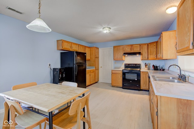 kitchen featuring a textured ceiling, sink, black appliances, pendant lighting, and light hardwood / wood-style floors