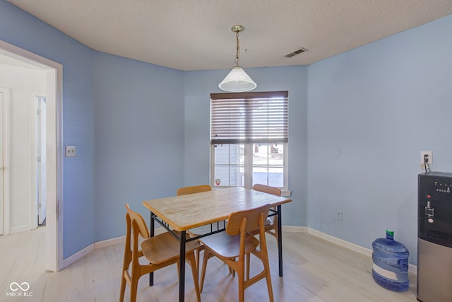 dining space with light hardwood / wood-style floors and a textured ceiling