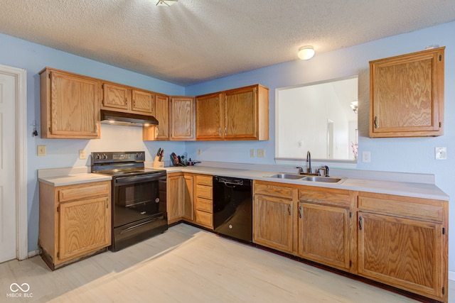 kitchen with sink, black appliances, a textured ceiling, and light wood-type flooring