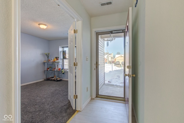 doorway featuring a textured ceiling and light colored carpet