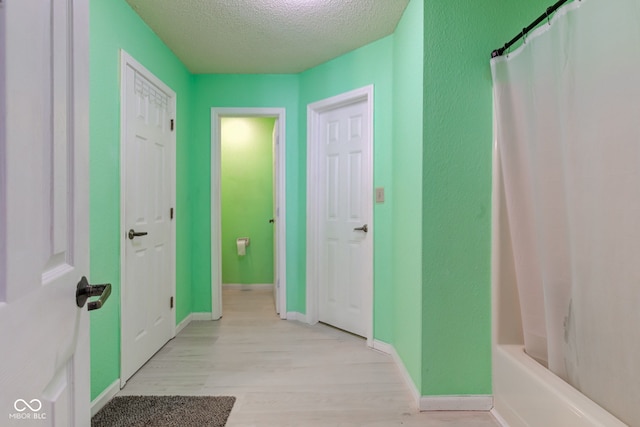 hallway with a textured ceiling and light hardwood / wood-style floors