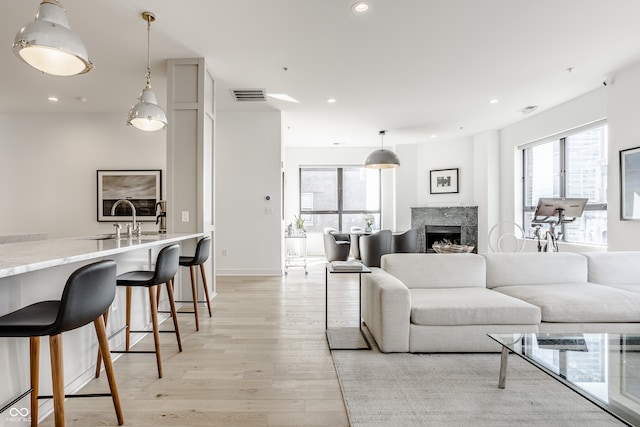 living room featuring light hardwood / wood-style floors, a high end fireplace, and sink