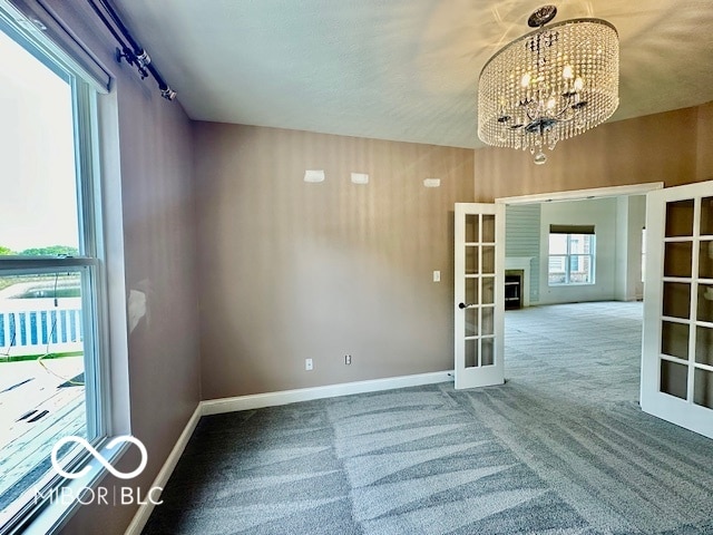 unfurnished room with light carpet, a notable chandelier, and french doors