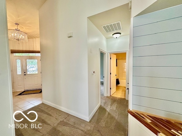 hall featuring light colored carpet and an inviting chandelier