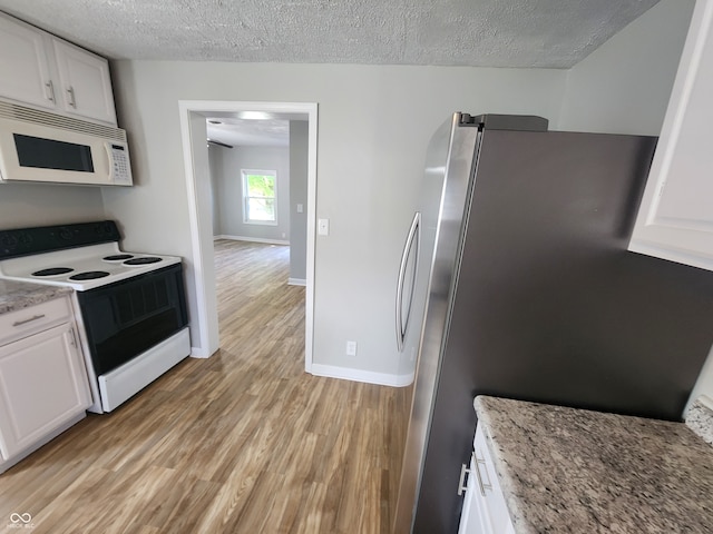 kitchen featuring light wood-type flooring, white appliances, white cabinets, and a textured ceiling