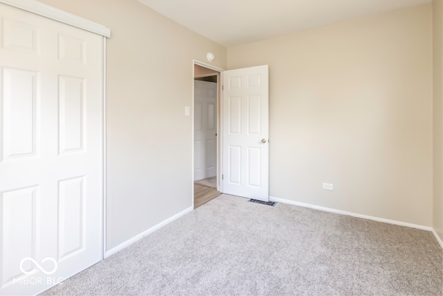 unfurnished bedroom with light colored carpet and a closet