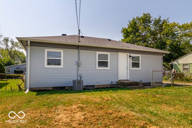 back of house with central air condition unit and a yard