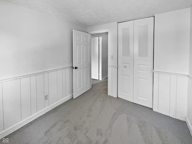 unfurnished bedroom with a closet, a textured ceiling, and carpet floors