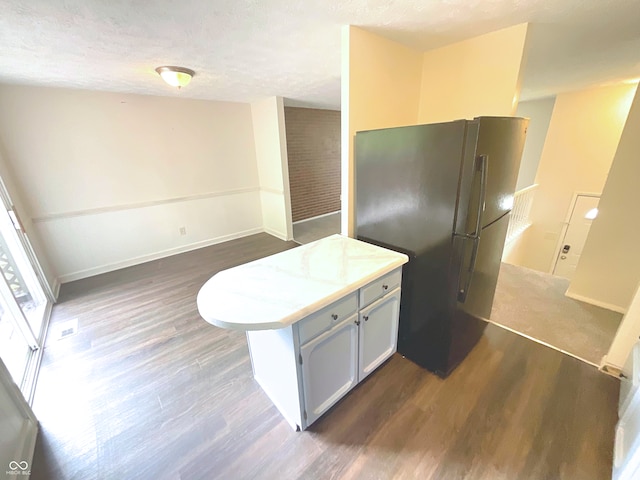 kitchen with a textured ceiling, dark hardwood / wood-style floors, and black fridge