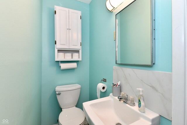 bathroom with backsplash, toilet, and sink