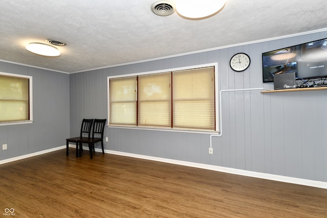 unfurnished room featuring dark wood-type flooring, crown molding, and a textured ceiling