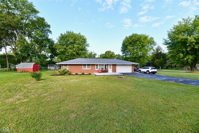 ranch-style home with a garage, a storage shed, and a front lawn