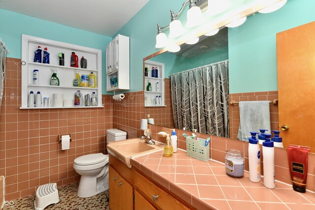 bathroom featuring a shower with shower curtain, vanity, toilet, and tile walls