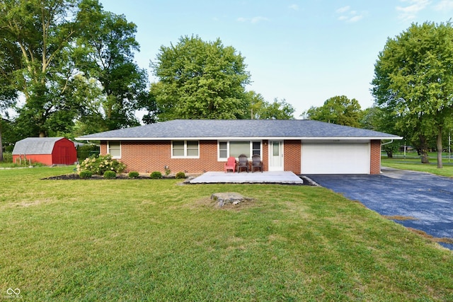 single story home featuring aphalt driveway, an outdoor structure, a front lawn, a garage, and a storage shed