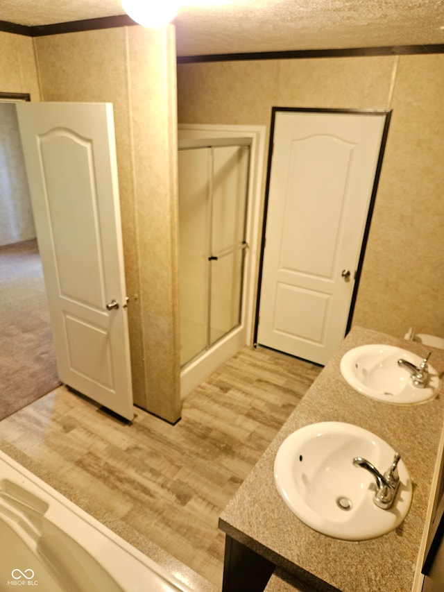 bathroom featuring crown molding, vanity, a textured ceiling, hardwood / wood-style flooring, and a shower with shower door