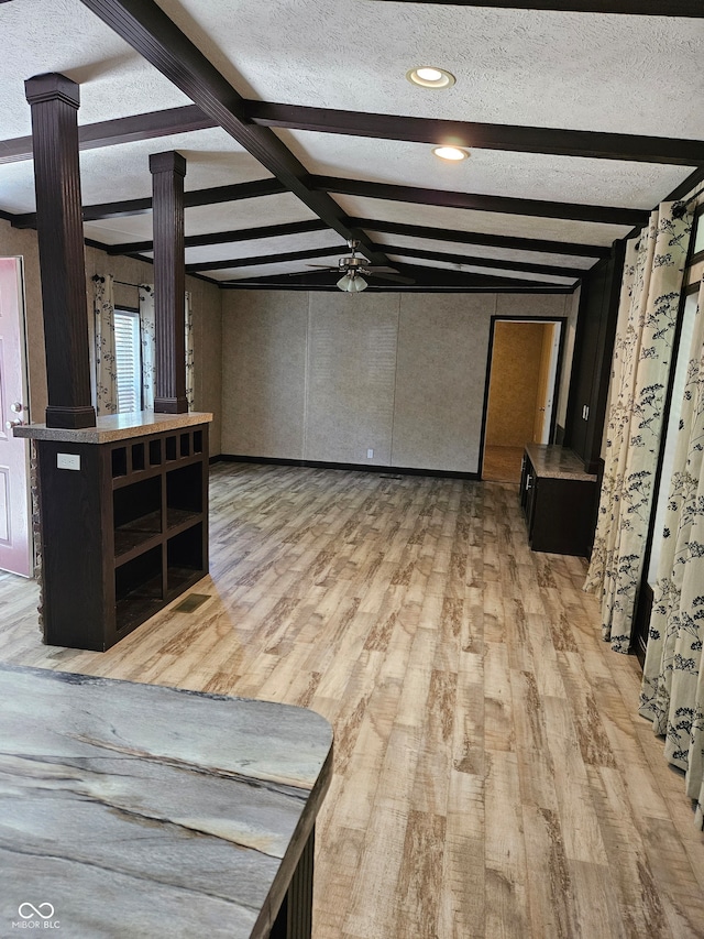 unfurnished living room with lofted ceiling with beams, a textured ceiling, wood-type flooring, and decorative columns