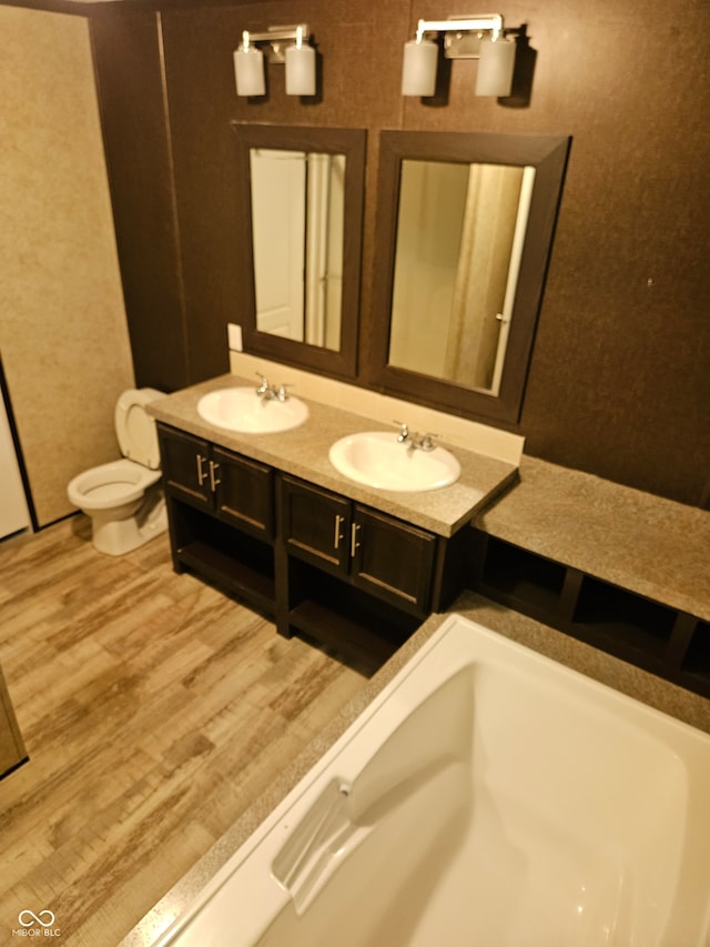 bathroom featuring hardwood / wood-style floors, a tub to relax in, toilet, and vanity