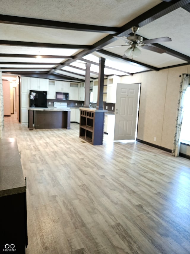 unfurnished living room with a textured ceiling, light hardwood / wood-style flooring, ceiling fan, vaulted ceiling with beams, and ornate columns