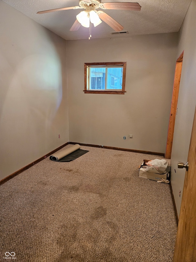 carpeted empty room featuring ceiling fan and a textured ceiling