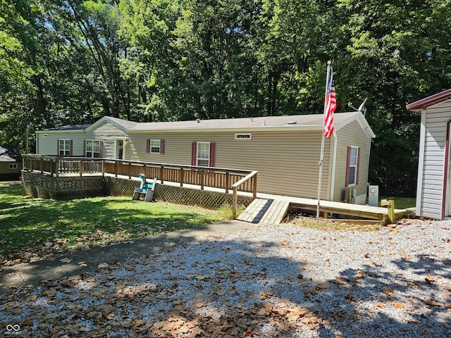 rear view of property featuring a wooden deck and a lawn