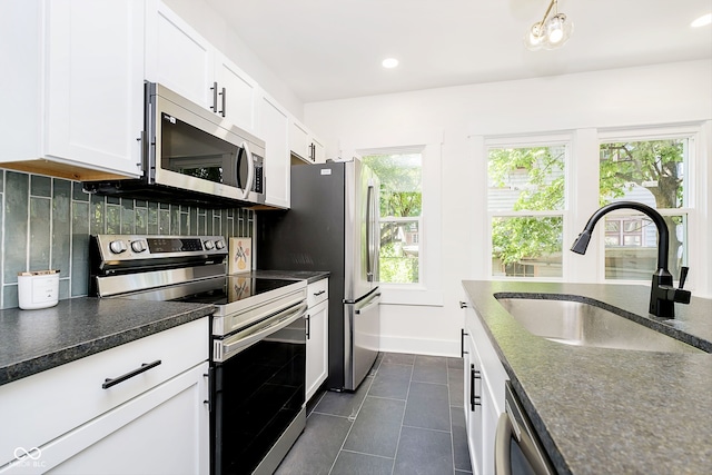 kitchen featuring dark tile patterned flooring, stainless steel appliances, sink, decorative backsplash, and white cabinets