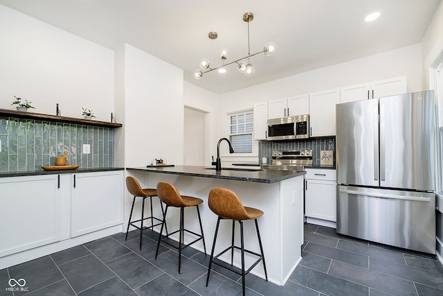 kitchen with white cabinetry, backsplash, decorative light fixtures, stainless steel appliances, and a breakfast bar area