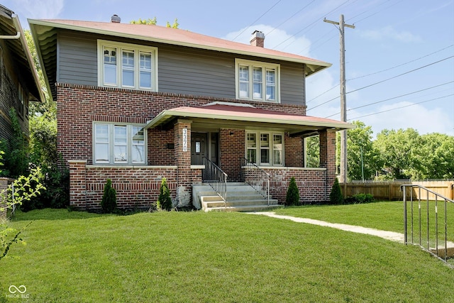 american foursquare style home with a front lawn, fence, and brick siding