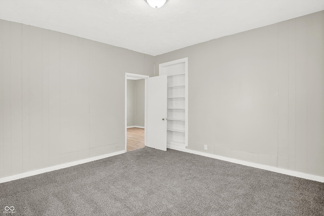 empty room with built in shelves and carpet floors