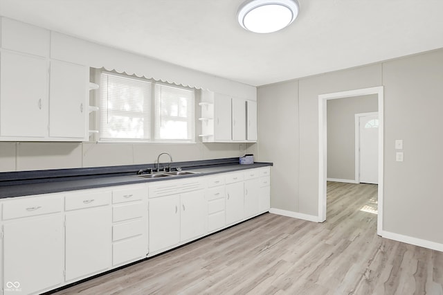 kitchen with light hardwood / wood-style floors, white cabinetry, and sink