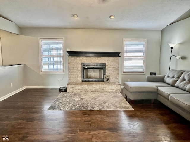 unfurnished living room with a wealth of natural light, baseboards, wood finished floors, and a fireplace