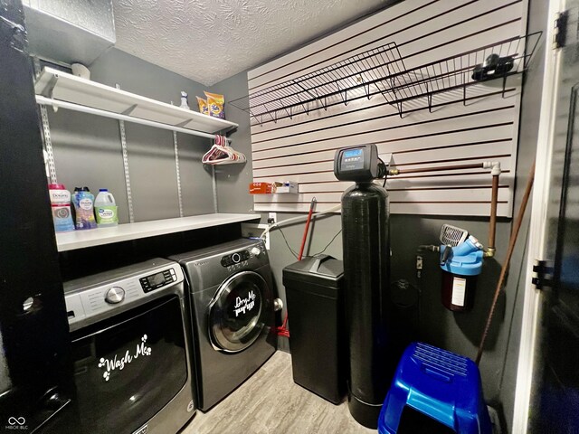 clothes washing area featuring washer and dryer, a textured ceiling, and hardwood / wood-style flooring