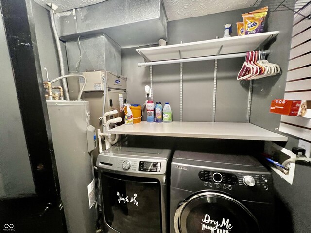 clothes washing area with electric water heater, washer and clothes dryer, and a textured ceiling