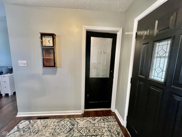 foyer featuring a textured ceiling and dark hardwood / wood-style floors