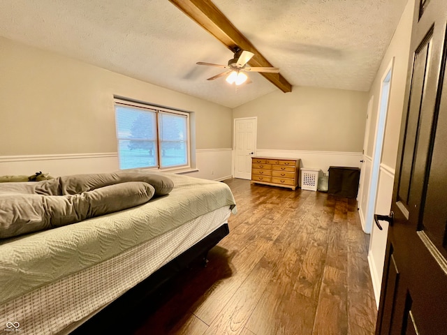 bedroom with ceiling fan, lofted ceiling with beams, a textured ceiling, and hardwood / wood-style flooring