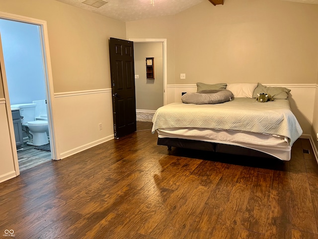 bedroom with a textured ceiling, dark hardwood / wood-style floors, ensuite bath, and vaulted ceiling