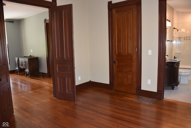 bedroom with connected bathroom, hardwood / wood-style floors, and sink