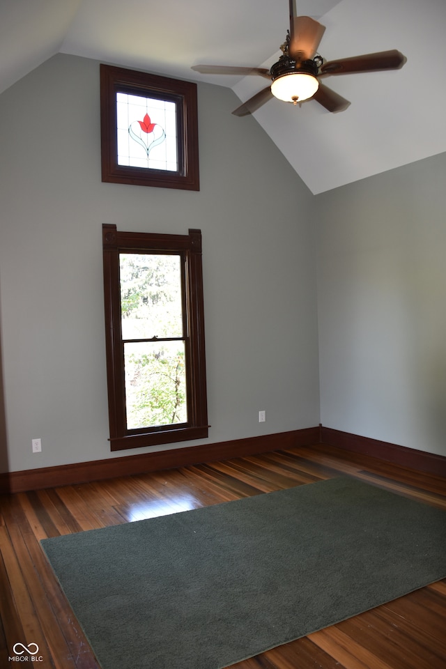 unfurnished room featuring plenty of natural light, vaulted ceiling, ceiling fan, and dark hardwood / wood-style floors