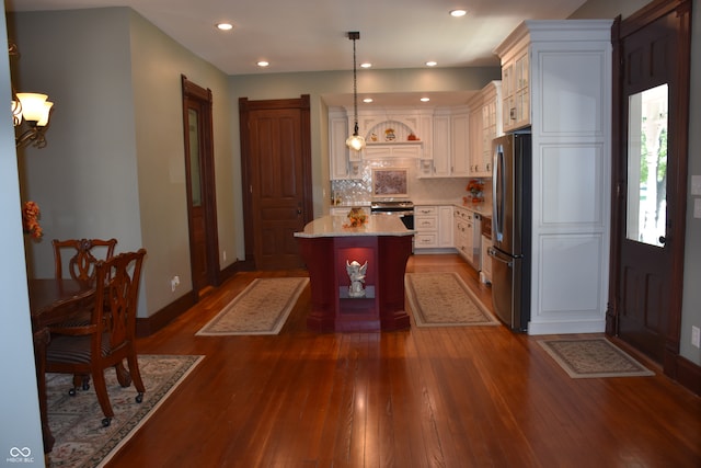 kitchen with appliances with stainless steel finishes, a kitchen breakfast bar, dark wood-type flooring, a center island, and decorative light fixtures