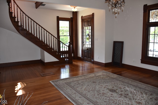 entrance foyer featuring plenty of natural light, dark hardwood / wood-style floors, and a chandelier