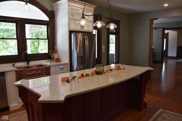 kitchen featuring hanging light fixtures, light stone counters, dark hardwood / wood-style flooring, stainless steel refrigerator with ice dispenser, and sink