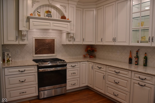 kitchen with light stone counters, tasteful backsplash, stainless steel stove, white cabinetry, and dark hardwood / wood-style flooring