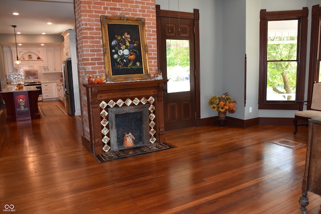 living room with dark hardwood / wood-style flooring and a brick fireplace