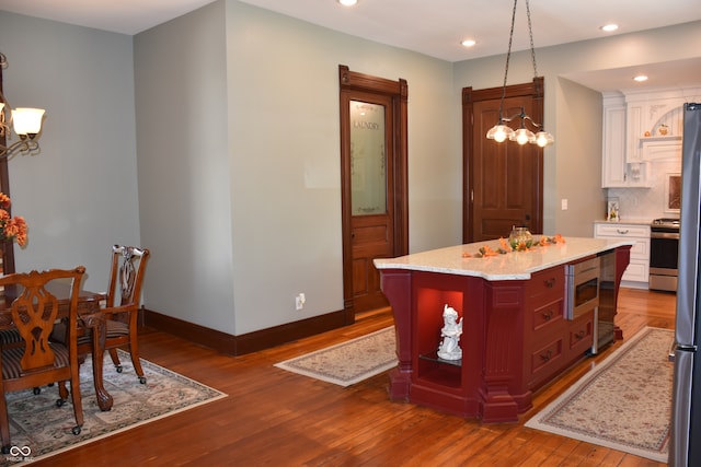 kitchen featuring appliances with stainless steel finishes, wood-type flooring, a kitchen island, and pendant lighting