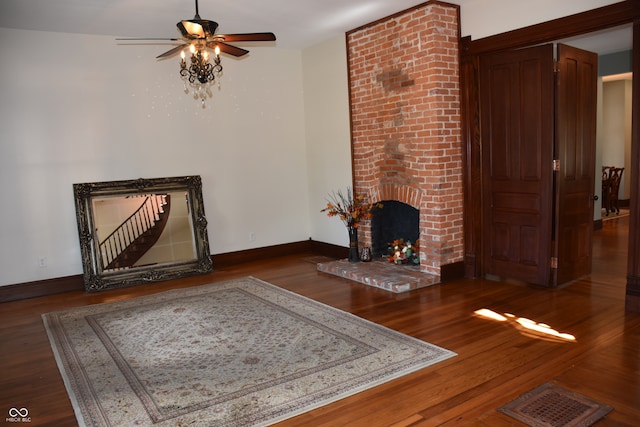 unfurnished living room featuring a fireplace, dark hardwood / wood-style floors, and ceiling fan