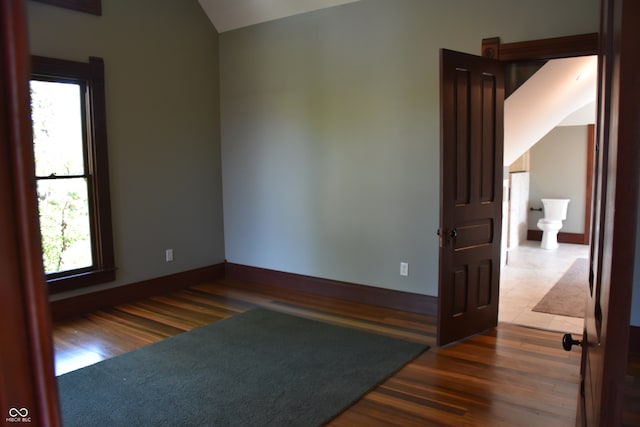 unfurnished room with lofted ceiling and dark wood-type flooring