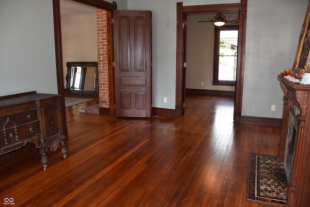 interior space with ceiling fan, dark hardwood / wood-style floors, and a fireplace