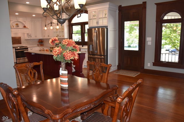 dining room featuring a notable chandelier, sink, dark wood-type flooring, and a wealth of natural light