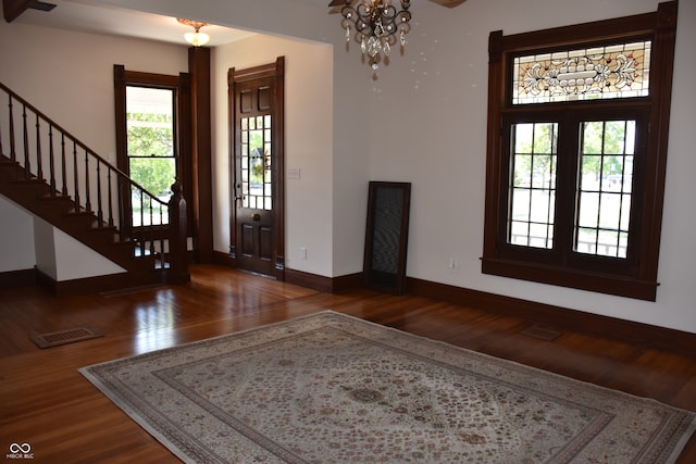 foyer with french doors, a chandelier, dark wood-type flooring, and a wealth of natural light