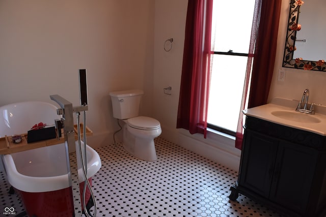 bathroom featuring a wealth of natural light, vanity, a washtub, and toilet